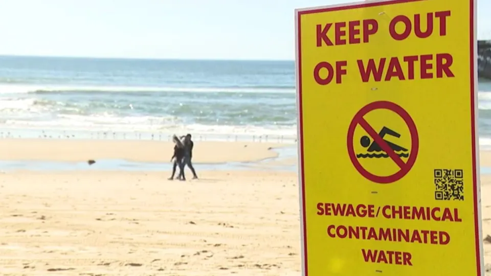 Keep out of water sign in foreground of beach